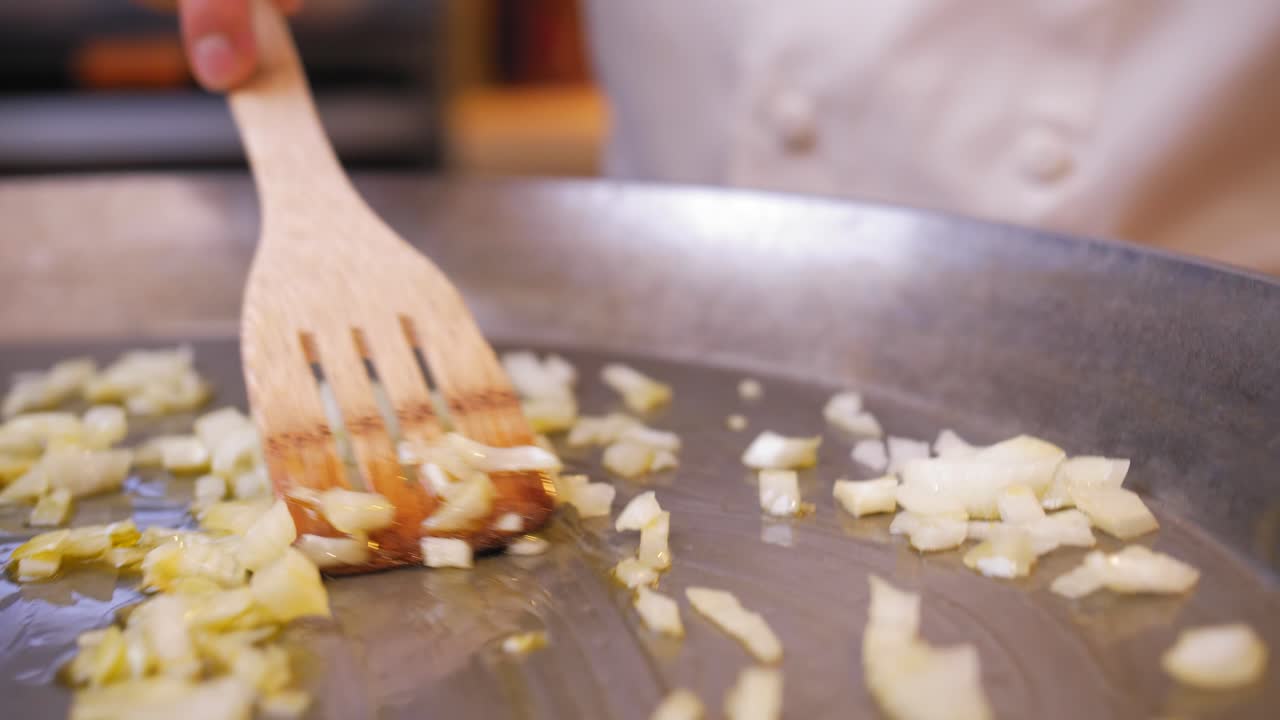 the cook mixes the onions in the pan