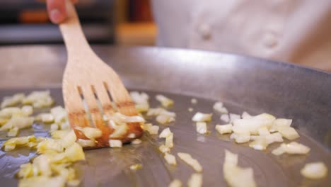 el cocinero mezcla las cebollas en la sartén