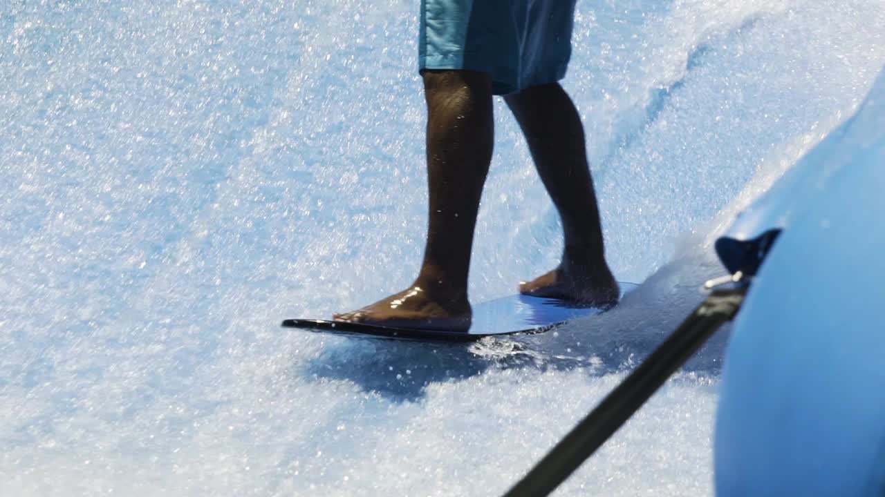 Skicklig surfare carvar på vågmaskin i slowmotion