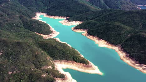 camión aéreo a la derecha del embalse de la isla alta colinas verdes, columnas de roca en la orilla y agua turquesa, península de san kung en hong kong, china