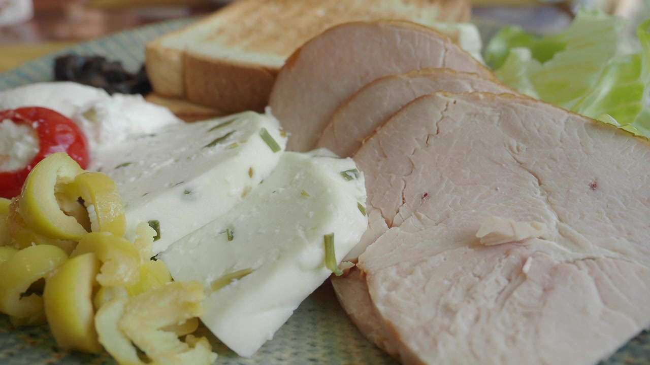 Piatto da colazione appetitoso con tacchino a fette, formaggio feta e olive