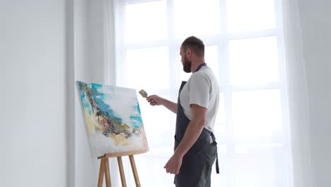 an artist paints a piece of art on a canvas with color oil painting at home an artist works and - an artist paints a piece of art on a canvas with color oil painting at home. an artist works and creatively works on an abstract oil painting in the workshop. hobby concept