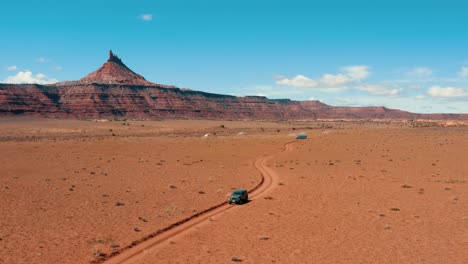 Drone-aerial-view-of-jeep-driving-with-Six-Shooter-Peaks-in-Indian-Creek-region-of-Bears-Ears-National-Monument,-Utah