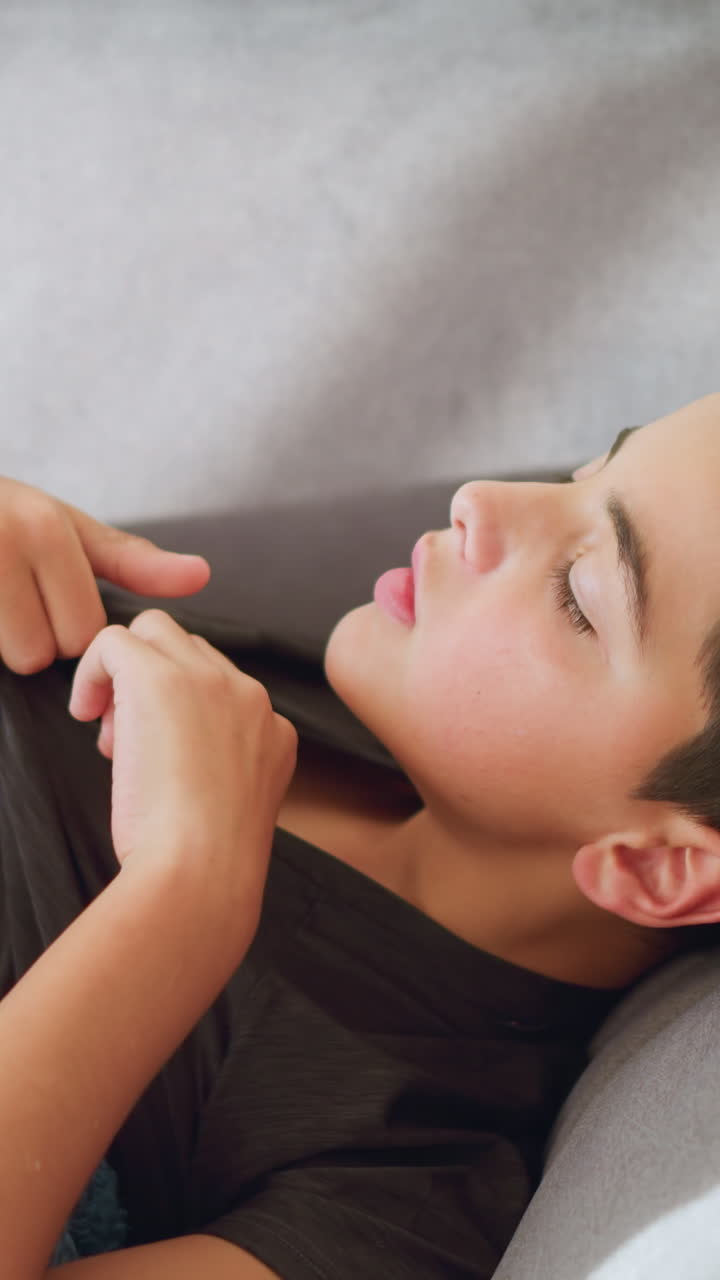 Close-up of sick boy collecting thermometer from someone to check his temperature while covered with blanket, sign of illness, at-home care, health check, resting and monitoring