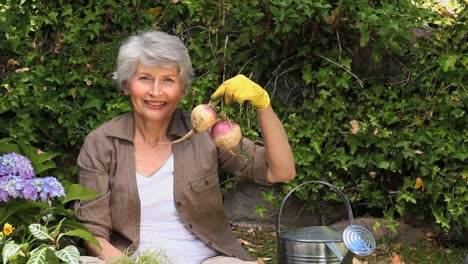 old woman gardening and smiling at the camera