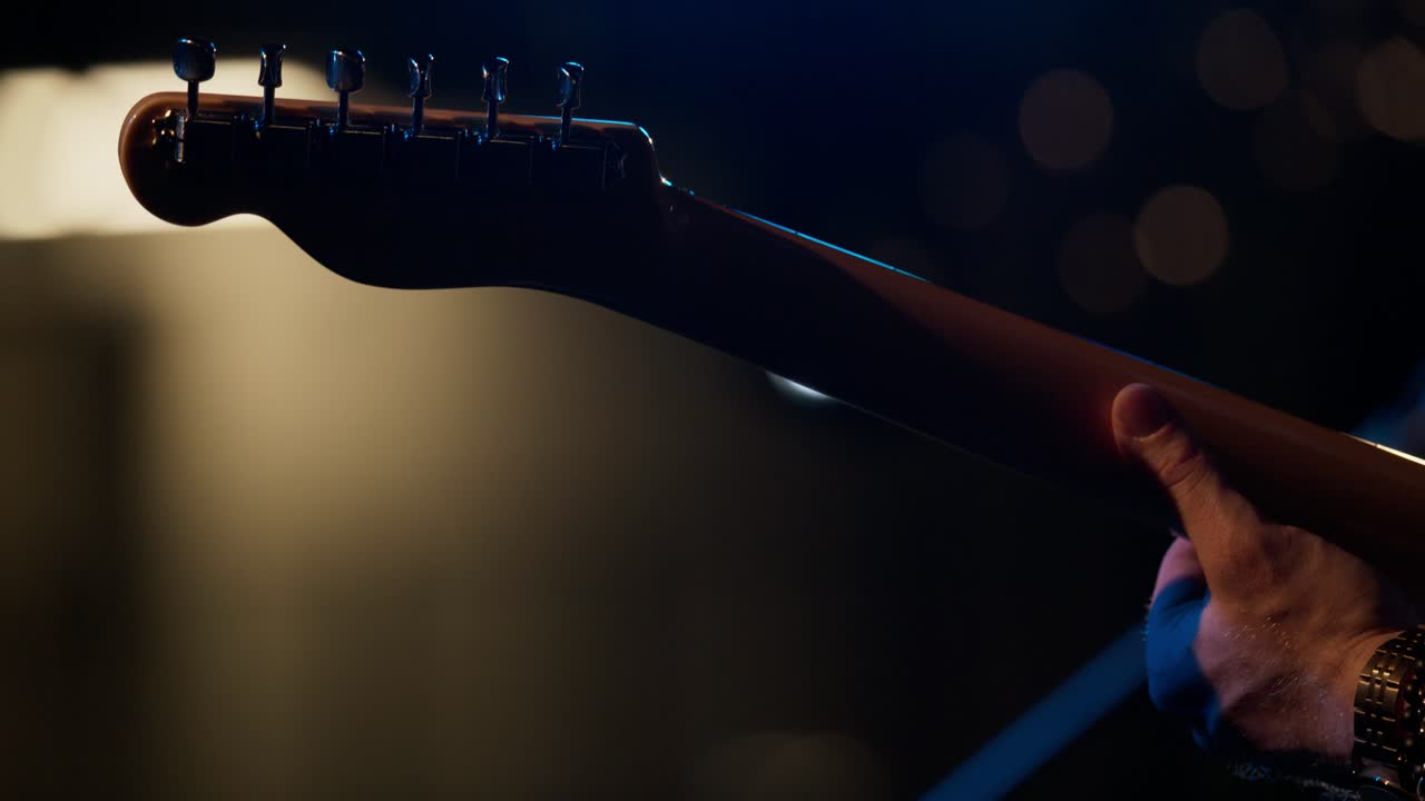 Musicista suona la chitarra elettrica sotto luci di scena brillanti. Rallentatore.
