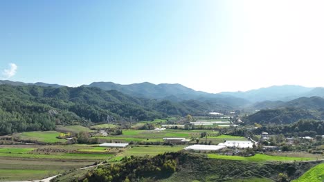 areal shot of farming fields and greenhouses located in the mountains on a sunny day 4k 60 fps