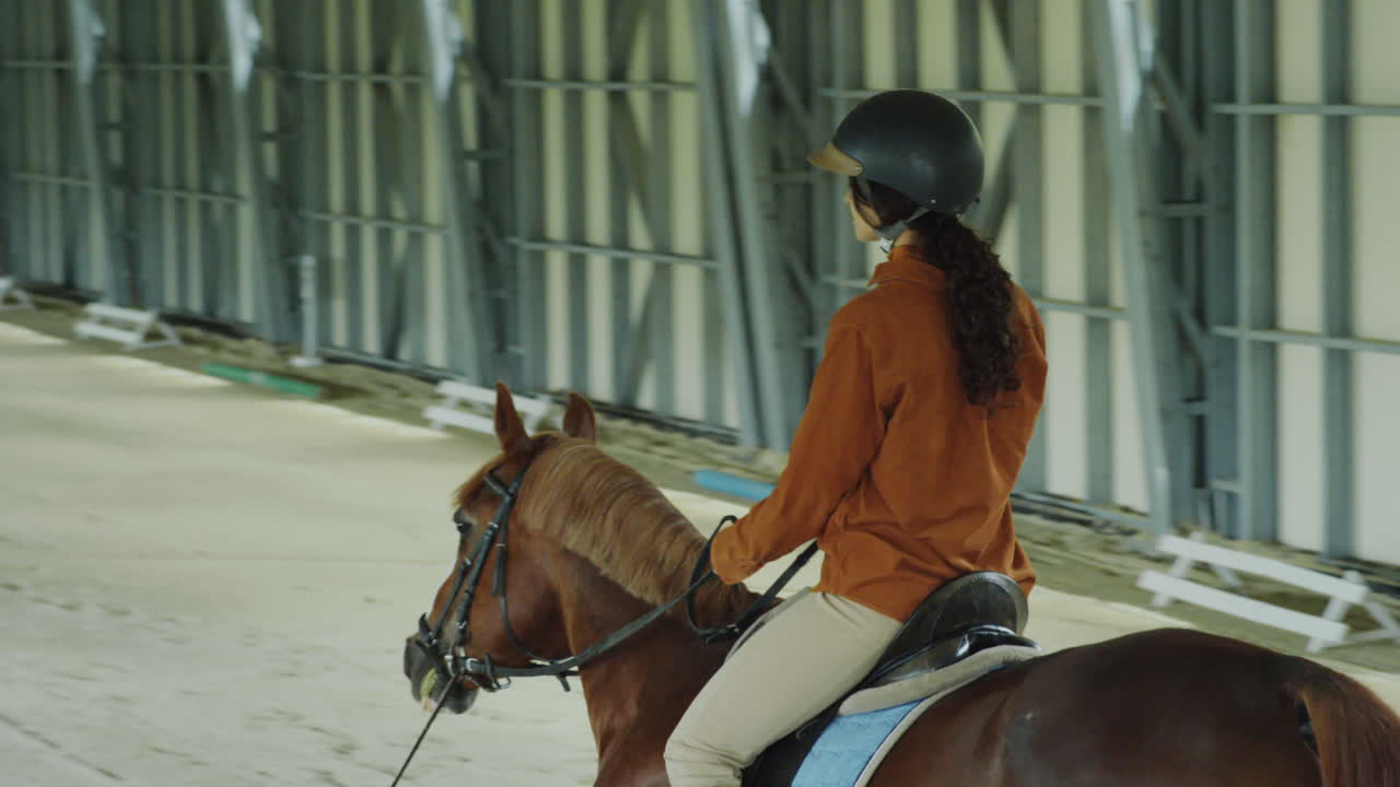 A woman riding a horse in an indoor equestrian arena