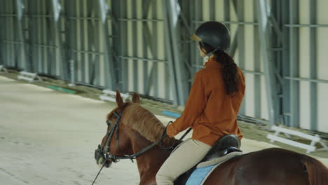 a woman riding a horse in an indoor equestrian arena