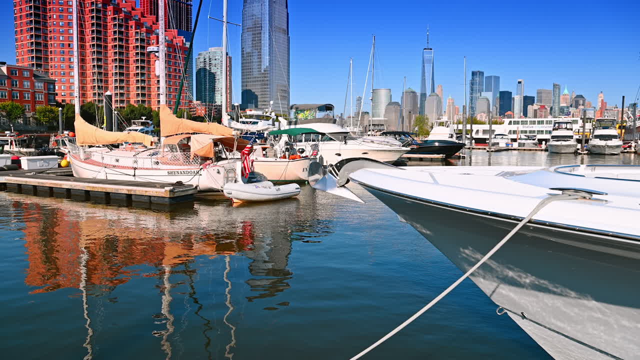 Multiple boats and yachts stand anchored at the berths. Boating and sailing in Jersey, USA. Manhattan skyline at backdrop