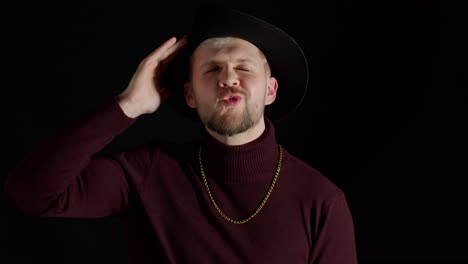 Facial-expression-of-handsome-man-in-stylish-hat-looking-at-camera-and-smiling-on-black-background