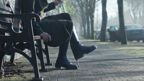 woman in black boots stands up from bench and walks down misty street