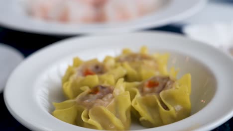 A-steamed-Shumai-dumpling-dish-is-seen-in-the-foreground-displayed-on-a-table-as-part-of-a-Cantonese-culinary-food-and-dim-sum-experience