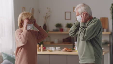 Senior-Couple-Putting-On-Protective-Masks-at-Home