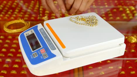 digital scales for weighing gold rings and necklaces with hand in store