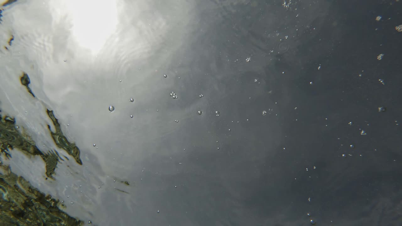 Tiny Stones Drop On Clearwater Ocean Making Bubbles. Close Up