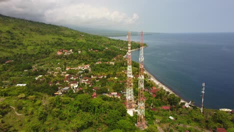 Antenne-5g-Telekommunikationsturmpaarpaare-über-Einer-Klippe-Mit-Blauem-Wassermeerblick-Und-Grüner-Natürlicher-Vegetation-Des-Dschungels,-Daten-Drahtlose-Smartphone-Internet-Social-Media-Verbindung