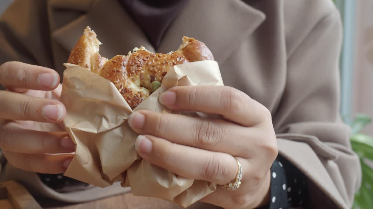 Una mujer comiendo un sándwich.