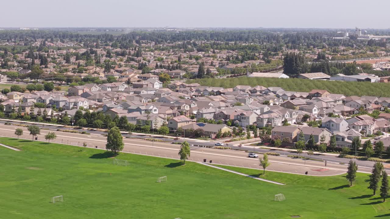 Drone che si muove in avanti sopra un campo da calcio verso case e strada