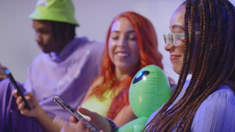 fotografía de estudio de cerca de amigos jóvenes de la generación z sentados en el sofá hablando y compartiendo publicaciones en las redes sociales en teléfonos móviles 8