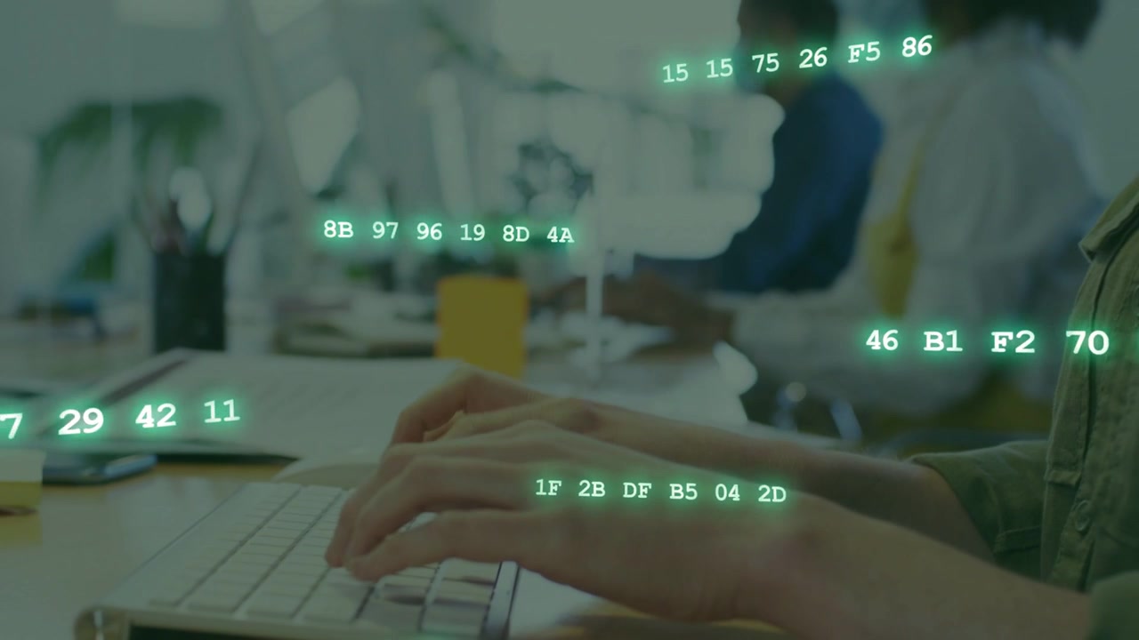 Empleado de oficina escribiendo en un teclado blanco en un escritorio compartido, generando cadenas de datos verdes que soportan la programación.