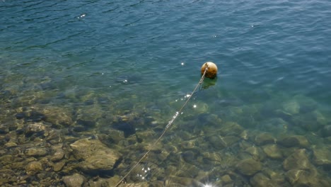 a tied up orange mooring buoy floating in vibrant blue sea