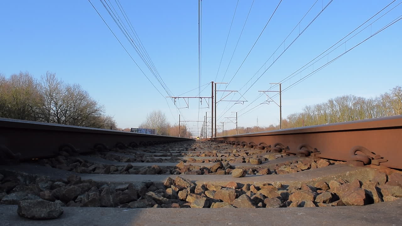 A train approaches and passes over the camera. Shot from between the train rails.