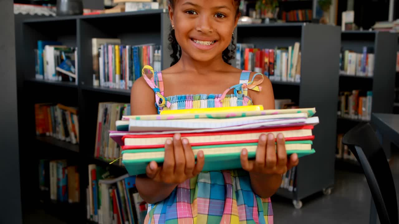 retrato de una estudiante feliz de pie con una pila de libros 4k
