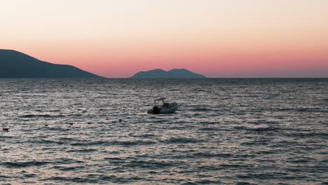 Vista-Tranquila-Del-Barco-Flotante-En-El-Mar-Con-Silueta-De-Montaña-De-Color-Atardecer