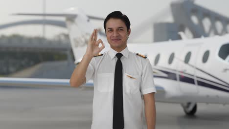 happy indian pilot showing okay sign