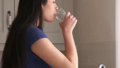 Una-Mujer-Joven-Y-Bonita-Bebiendo-Agua-En-La-Cocina.