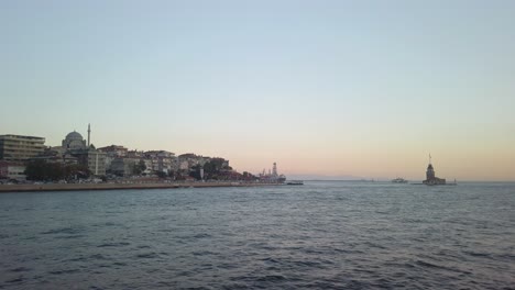 noche, cámara lenta cinematográfica, la vista de uskudar y la adyacente torre de la doncella desde un ferry que navega a lo largo del bósforo de estambul