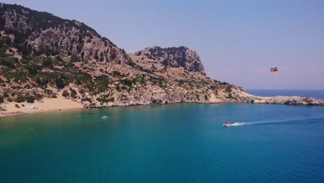 Parasailing-Auf-Ruhigem-Blauem-Meer-Mit-Felsiger-Landzunge-Im-Hintergrund