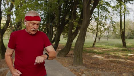 elderly sport man stops after running, using smart watch, checking heart rate during fitness