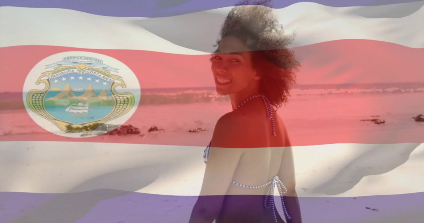 Modelo feminina caminhando na praia em anúncio de viagem, acionada pela câmera, virando-se para a câmera com sobreposição de bandeira.
