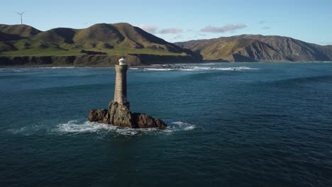 Alejándose-Del-Faro-De-Roca-Karori-Con-Tierra-En-El-Fondo,-Costa-Sur-De-Welligton,-Nueva-Zelanda