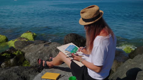 woman painting seascape on the beach