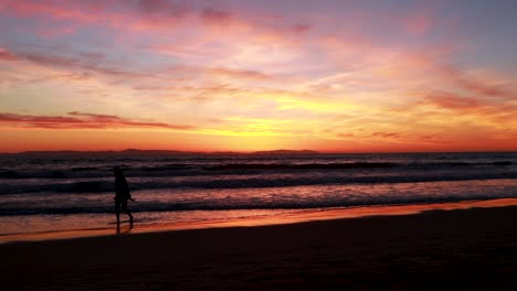 a disfruta de sus vacaciones en la playa durante una hermosa puesta de sol amarilla, naranja, rosa y azul con el muelle de huntington beach al fondo en surf city usa california