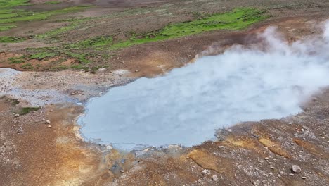 Una-Vista-Aérea-De-Un-Dron-Con-Un-Movimiento-Rápido,-Luego-Fijada-En-El-Lago-De-Vapor-De-Engjahver-En-La-Península-De-Reykjanes-En-Islandia