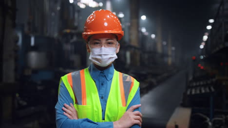 masked engineer crossing hands wearing face mask at modern special factory.