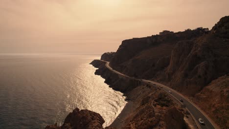 toma aérea de un largo camino construido al pie de altas montañas, vistas panorámicas al mar, almería