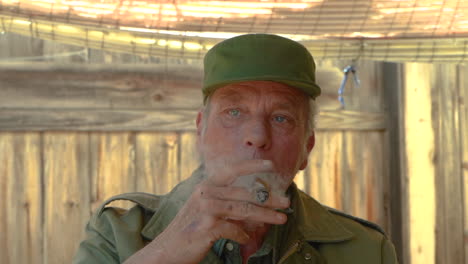 slow motion clip of an old handsome guy in army clothes, smoking a cigar