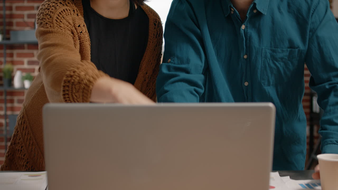 Two people working on a laptop at a desk in an office