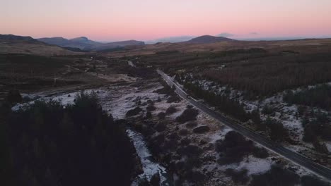 Verschneite-Landschaft-In-Der-Abenddämmerung-Mit-Kurvenreicher-Straße,-Skye,-Luftaufnahme