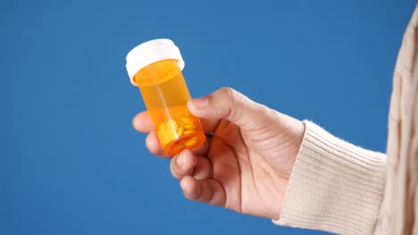 persona que sostiene una botella de pastillas