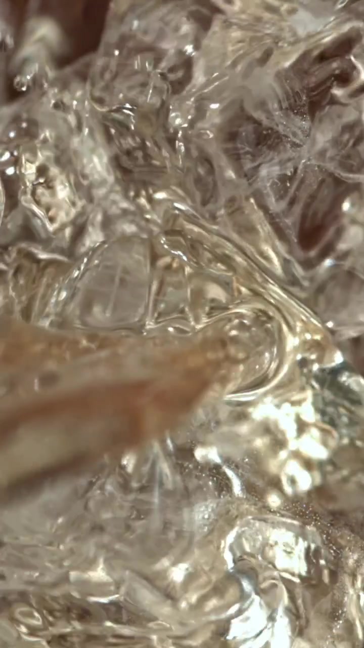 Primo piano di acqua che si versa su cubetti di ghiaccio trasparenti