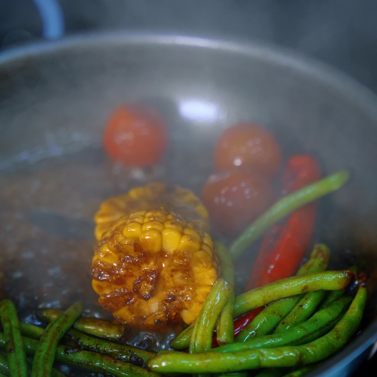 Beans, tomatoes, pepper, maize are stewed in soy sauce. Preparation of veggies in the frying pan. Close up. Vertical view