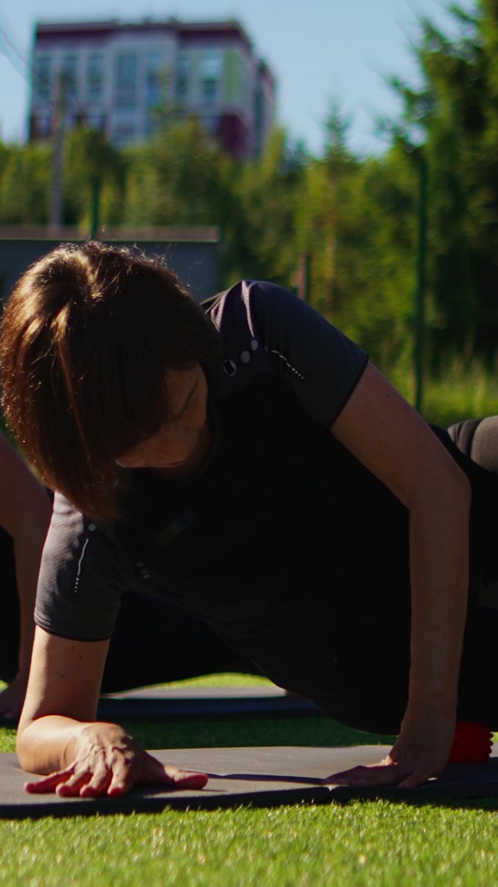 Donna che esegue l'esercizio di plank laterale su tappetino da yoga all'aperto