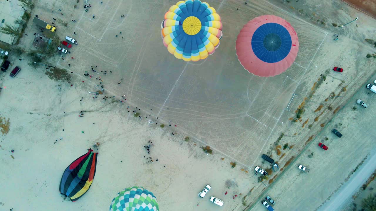 disparo de panorámica aérea volando sobre coloridos globos de aire caliente inflándose y preparándose para despegar durante el festival de globos