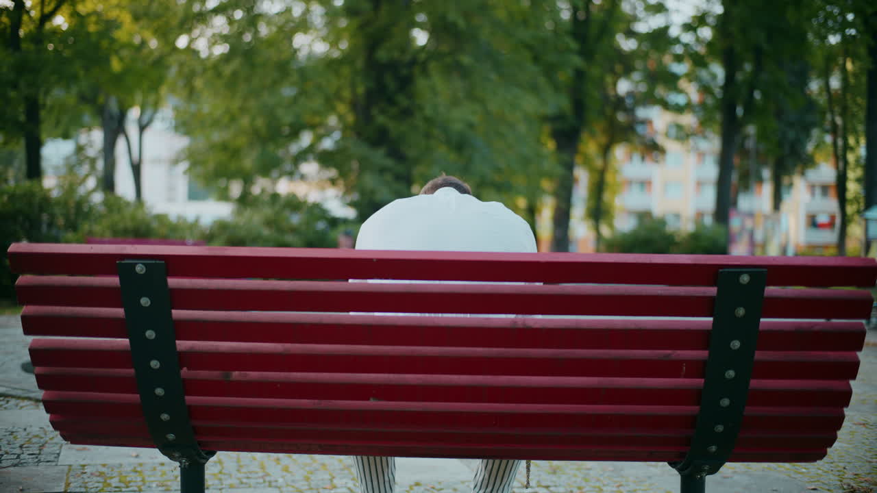 человек, сидящий один на скамейке в парке.